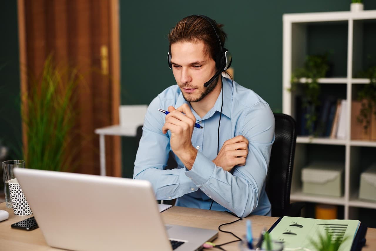 An accountant on a call with a headset, reviewing notes on a laptop.