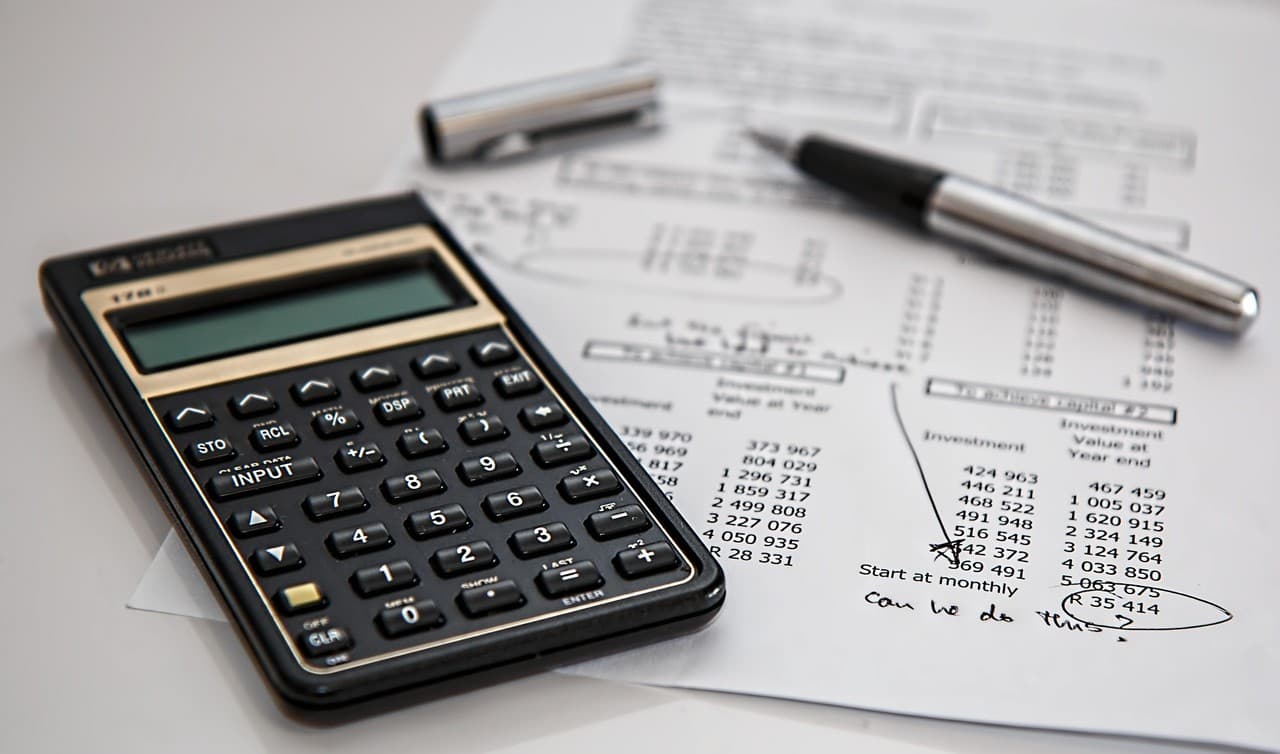 A calculator and pen resting on financial paperwork during a price review.